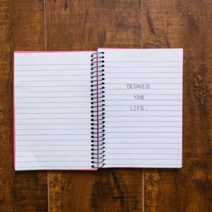 Open notebook with 'Organize Your Life' written, placed on wooden surface.