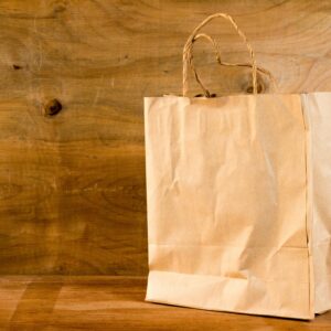 Close-up of a brown paper bag with handles on a wooden surface, offering warm earthy tones.