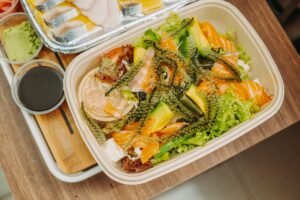 Delicious seafood salad with fresh seaweed, avocado, and salmon in a biodegradable container.