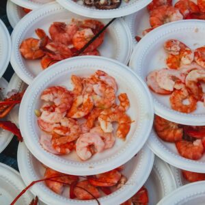 A variety of shrimp dishes served on disposable plates at an outdoor seafood market.