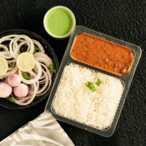 A vibrant Indian takeaway meal with rice, lentils, and fresh onions, perfect for lunch.
