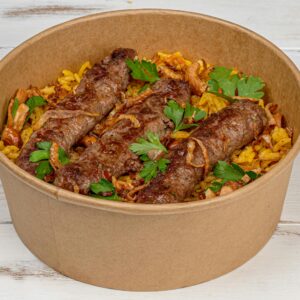 Appetizing grilled kebabs served with spiced rice in a biodegradable paper bowl.