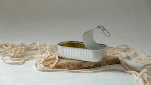 An open tin can lies on a rock slab, surrounded by rope in a studio setting.