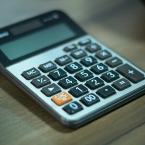 Digital calculator resting on a wooden table, selective focus.
