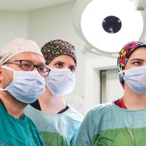 Team of surgeons focused during a procedure in a well-lit operating room.