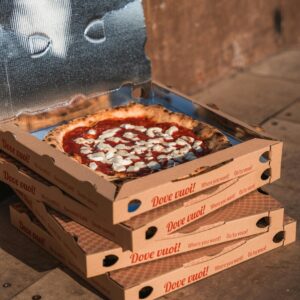 Delicious pizza in an open box atop stacked boxes, perfect for food delivery.