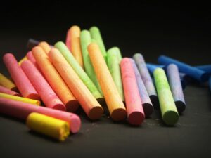 Vividly colored chalk sticks arranged on a dark surface, perfect for educational themes.