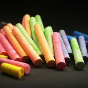 Vividly colored chalk sticks arranged on a dark surface, perfect for educational themes.
