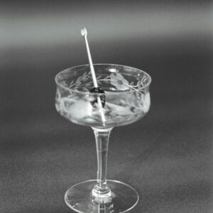 Elegant black and white still life of a cocktail glass with a cherry garnish on top.