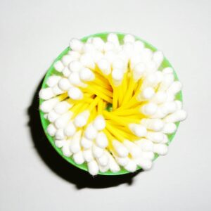 A close-up image of cotton swabs arranged inside a green plastic cup, viewed from above.