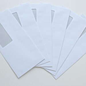 A set of white window envelopes fanned out on a flat surface, ready for mailing or office use.