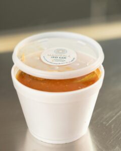 White to-go container with soup from Mashaal Restaurant in plastic cup.