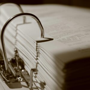 Detailed sepia close-up of a binder filled with documents, emphasizing texture.
