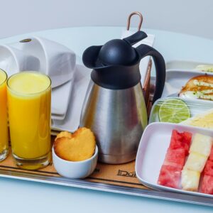 A well-presented hotel breakfast tray with fresh orange juice, fruits, and pastries, ideal for travel imagery.