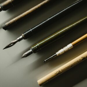 Close-up of vintage fountain pens and calligraphy nibs on a desk, showcasing writing tools.