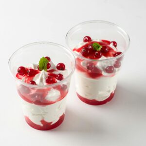 Two delicious red berry parfaits with cream, mint garnish in clear cups.