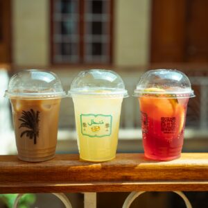 Three assorted beverages on a wooden railing indoors with artistic lighting.