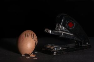 A conceptual image of a stapler 'repairing' a cracked egg with staples.