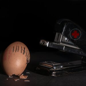 A conceptual image of a stapler 'repairing' a cracked egg with staples.