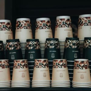 Colorful stack of paper coffee cups with geometric patterns in a cafe setting.