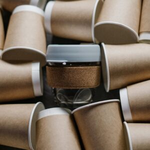 A reusable cup surrounded by paper cups emphasizes sustainability and zero waste.