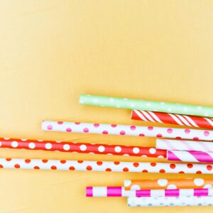 Vibrant paper straws with polka dots and stripes on a yellow background.
