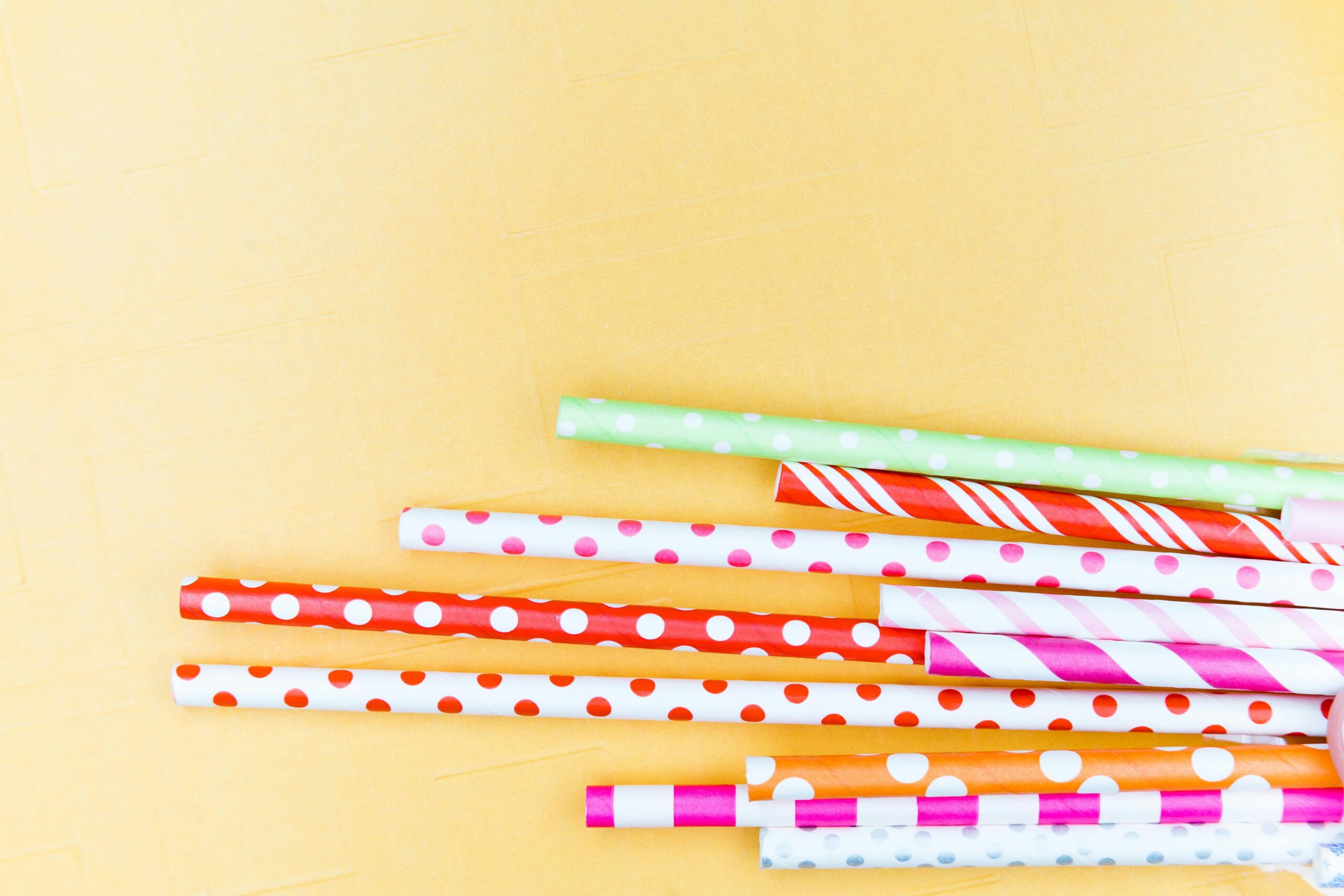pexels photo 4115385 4115385 Vibrant paper straws with polka dots and stripes on a yellow background.