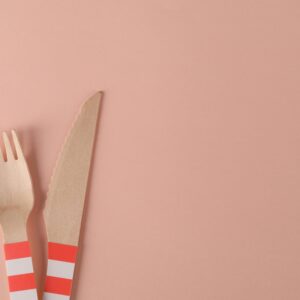 Eco-friendly wooden fork and knife set against a minimalist pink surface, perfect for sustainable lifestyle themes.