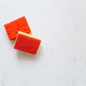 Two bright orange sponges suitable for cleaning against a white background.