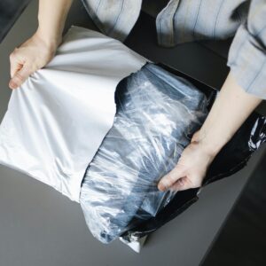 Close-up of a person unpacking a delivered parcel on a table indoors.