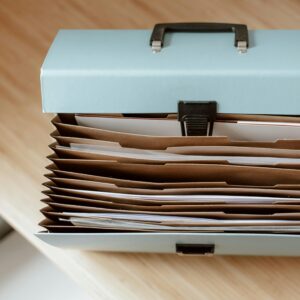 From above of briefcase for documents with papers placed on wooden table in daytime
