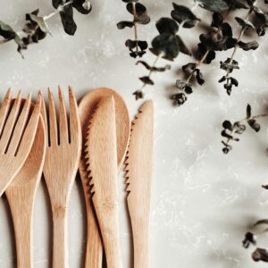 Close-up of bamboo utensils and eucalyptus branches on a marble surface, highlighting sustainability.