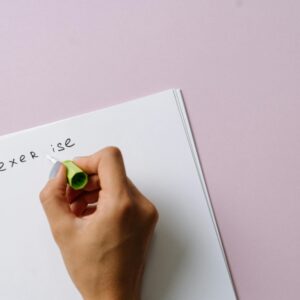 A hand using correction fluid to fix a spelling error on paper.