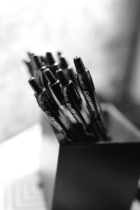 Black pens neatly arranged in a holder, captured in monochrome for a classic look.