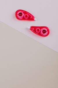 Close-up of two pink correction tapes on a beige and pink background.