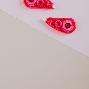 Close-up of two pink correction tapes on a beige and pink background.