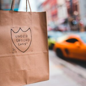 Paper bag with label on blurred background of pavement near road with cars