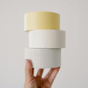 Crop unrecognizable person demonstrating various masking tapes for repair against white background at home