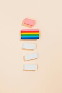 Colorful and white erasers arranged vertically on a soft pastel backdrop, minimalistic style.