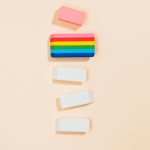 Colorful and white erasers arranged vertically on a soft pastel backdrop, minimalistic style.
