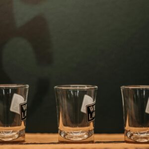 Three empty shot glasses aligned on a wooden table, ideal for bar or party themes.