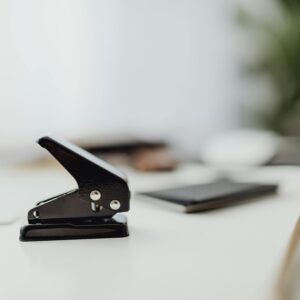 Close-up of a black hole puncher on a clean white desk in a minimalist office setting.