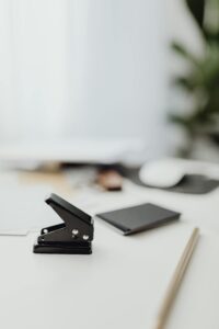 A clean, minimalist office desk featuring a paper stapler and supplies in soft focus.