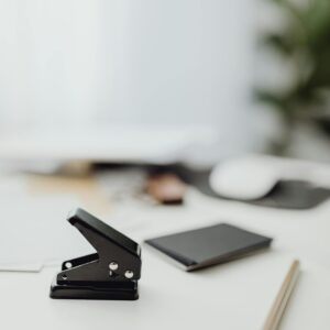 A clean, minimalist office desk featuring a paper stapler and supplies in soft focus.