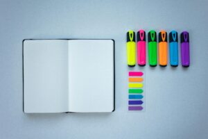 Flat lay of colorful highlighters and an open notebook, perfect for creative planning.