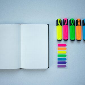 Flat lay of colorful highlighters and an open notebook, perfect for creative planning.