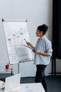 African American woman presenting data using graphs in a meeting room setting.