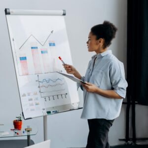 African American woman presenting data using graphs in a meeting room setting.