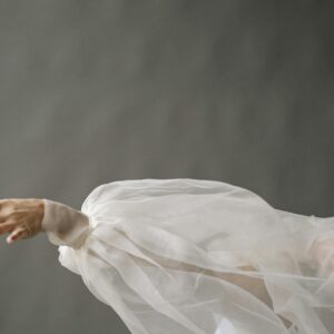 Elegant hand and arm draped in delicate white chiffon fabric, capturing graceful movement.