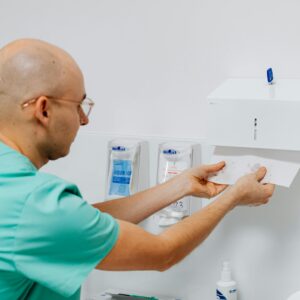 Doctor using a hand towel dispenser in a clinical setting, emphasizing hygiene.